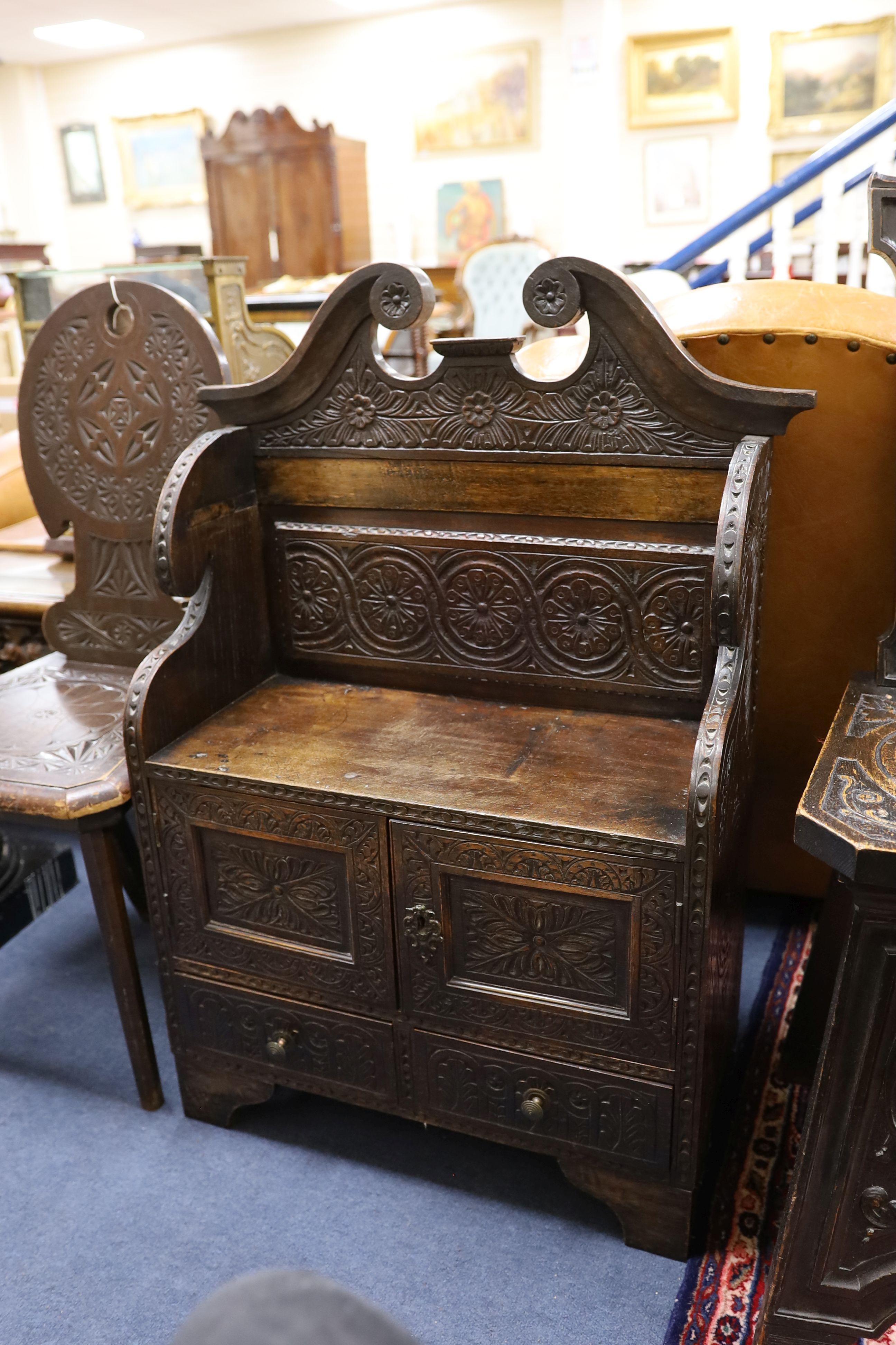 An early 20th century carved oak hall seat, width 64cm, depth 28cm, height 88cm together with two similar hall chairs